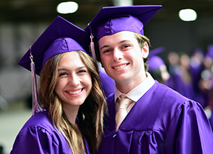 Male and female graduates smile at camera